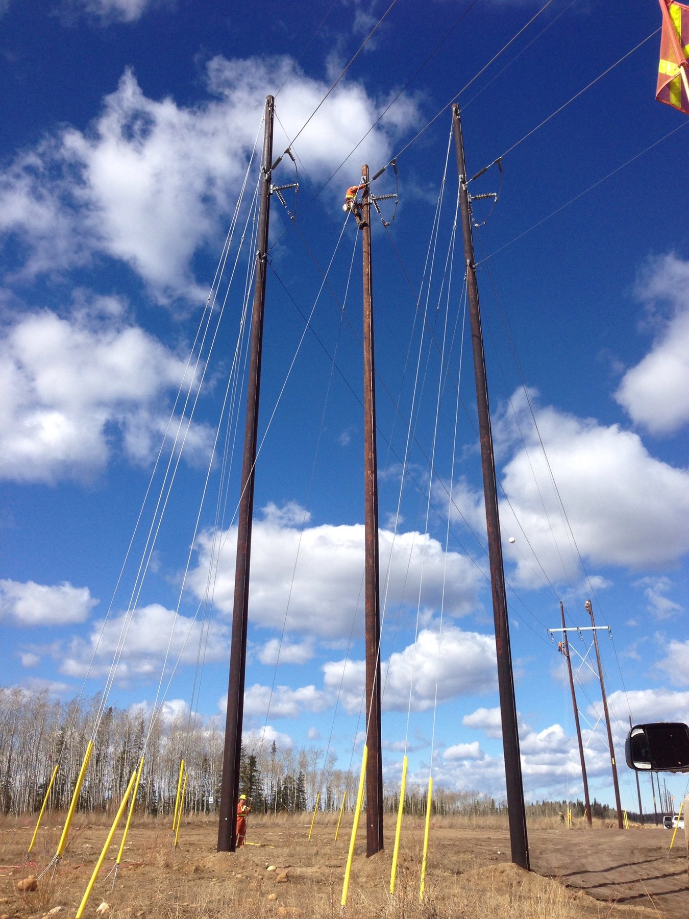 Powerline structures and field crew under a blue sky